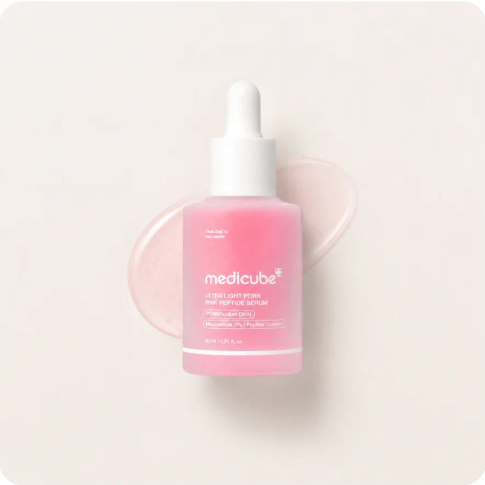 Pink skincare serum bottle with 'medicube' branding on a light beige background