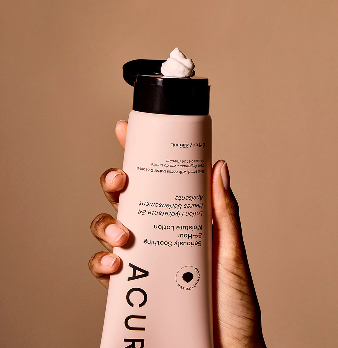 Hand holding Acure Seriously Soothing 24hr Moisture Lotion tube