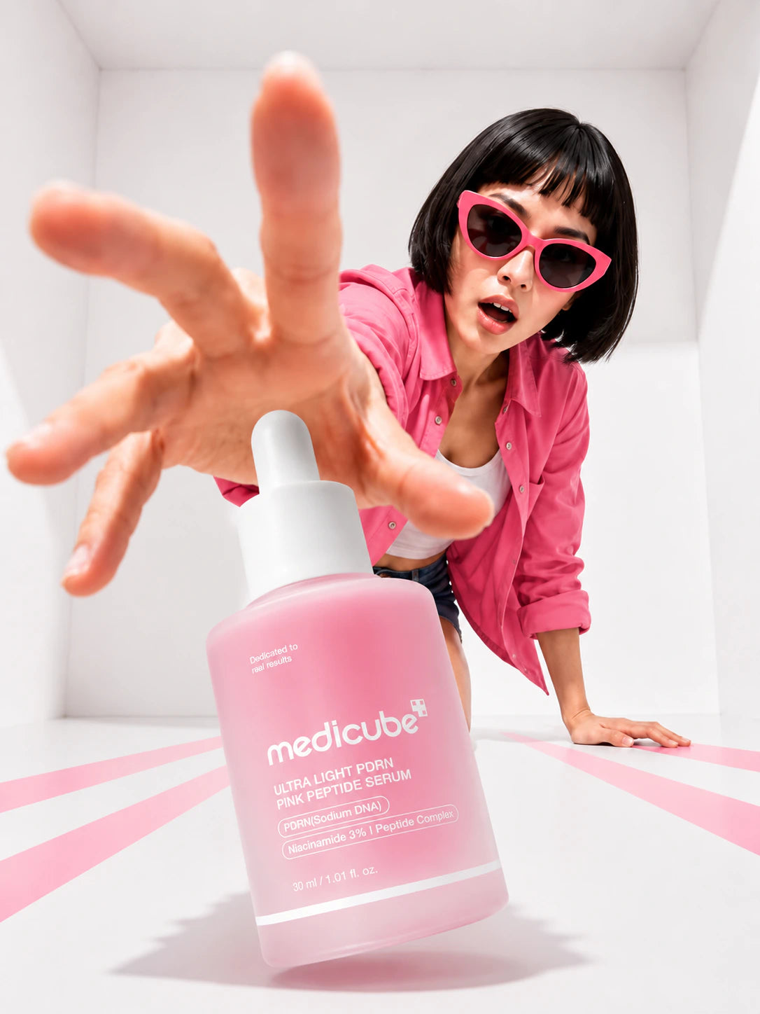 Person wearing pink sunglasses with a pink skincare serum bottle in front